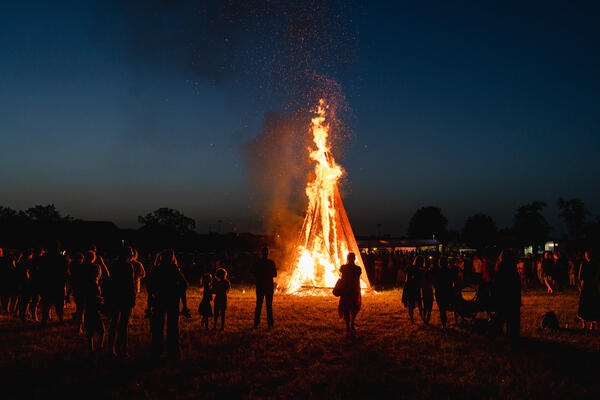 Menschen stehen um ein Sonnwendfeuer